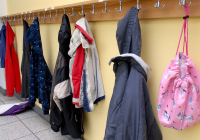 Jacken und Taschen an einer Hakenleiste in einem Schulflur