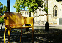 Gelber Stuhl steht auf dem Domplatz unter den Linden; im Hintergrund ist der Dom zu erkennen