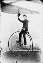 Schwarz-wei-Fotografie von 1885 eines jungen Mannes auf einem Hochrad, der seine Mtze schwingt.